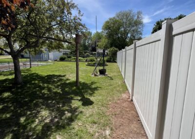 Greenville WI: White vinyl privacy fence running along a backyard property line
