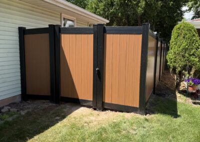Neenah WI: Two-tone vinyl privacy fence with a gate, cedar-look panels and black posts